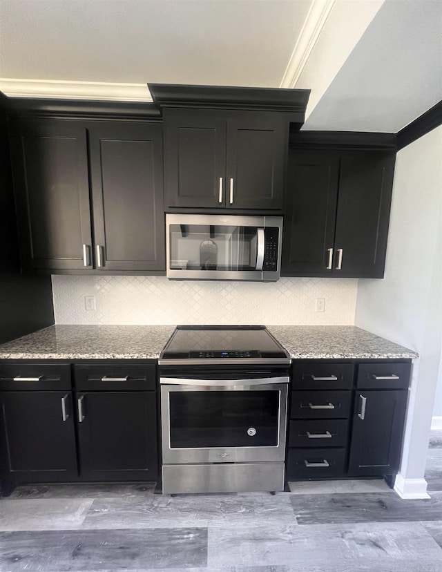 kitchen featuring backsplash, light stone counters, stainless steel appliances, light hardwood / wood-style floors, and crown molding