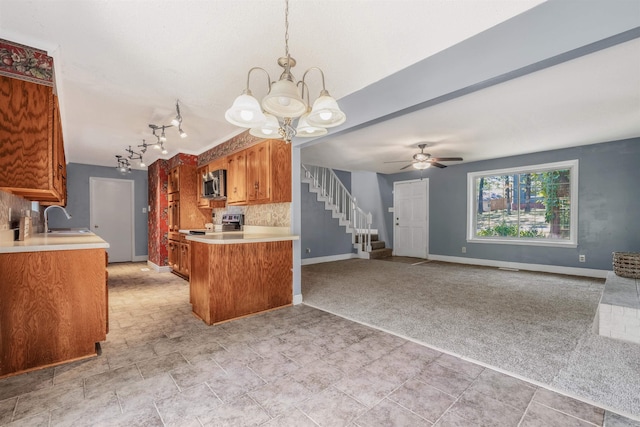 kitchen with sink, rail lighting, ceiling fan with notable chandelier, tasteful backsplash, and light colored carpet