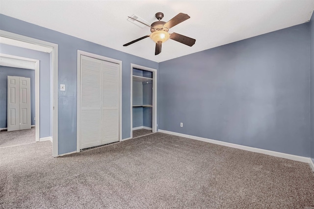 unfurnished bedroom featuring ceiling fan, carpet flooring, and multiple closets