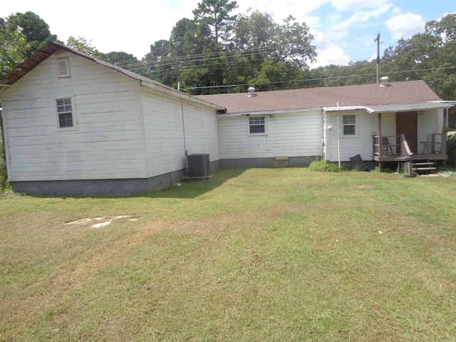 back of house featuring central AC unit and a lawn