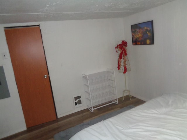 bedroom featuring radiator heating unit, electric panel, a textured ceiling, and dark hardwood / wood-style floors