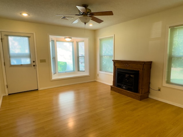 unfurnished living room featuring a textured ceiling, light hardwood / wood-style flooring, and ceiling fan