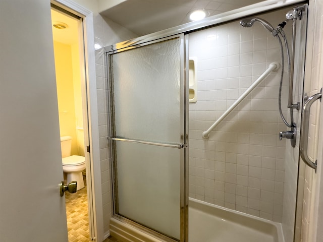 bathroom with a shower with door and toilet