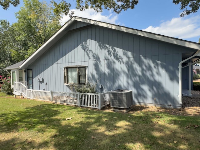 view of side of property featuring central air condition unit and a lawn