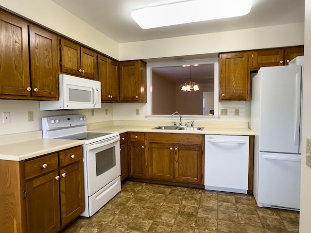 kitchen featuring sink, an inviting chandelier, dark tile patterned flooring, white appliances, and hanging light fixtures