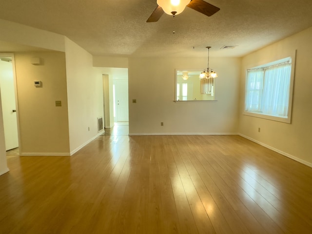 unfurnished room featuring a textured ceiling, ceiling fan with notable chandelier, and wood-type flooring