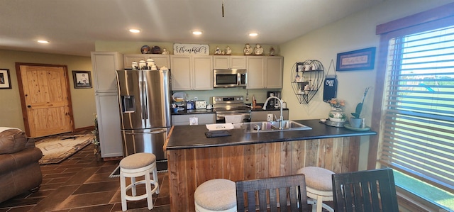 kitchen featuring sink, a kitchen breakfast bar, dark tile patterned floors, and stainless steel appliances