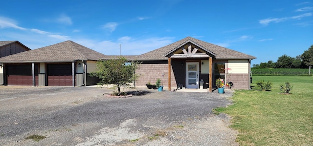 ranch-style home featuring a garage, a front lawn, and gravel driveway
