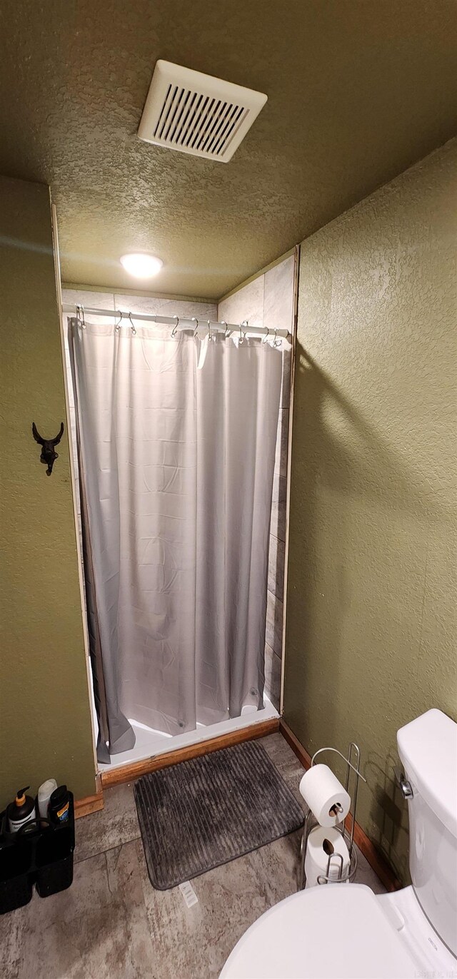 bathroom with a shower with shower curtain, a textured ceiling, and toilet