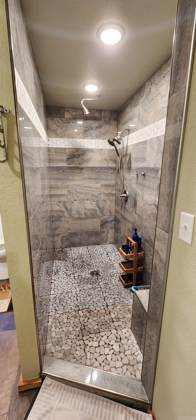 bathroom with tile patterned flooring and a tile shower