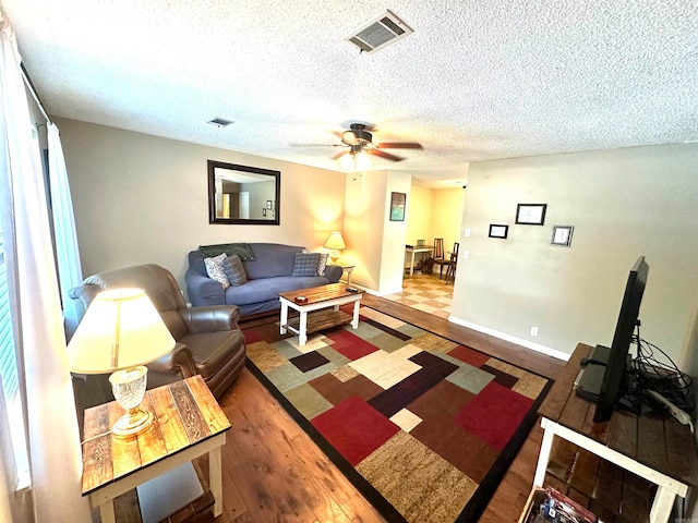 living room with hardwood / wood-style floors, ceiling fan, and a textured ceiling