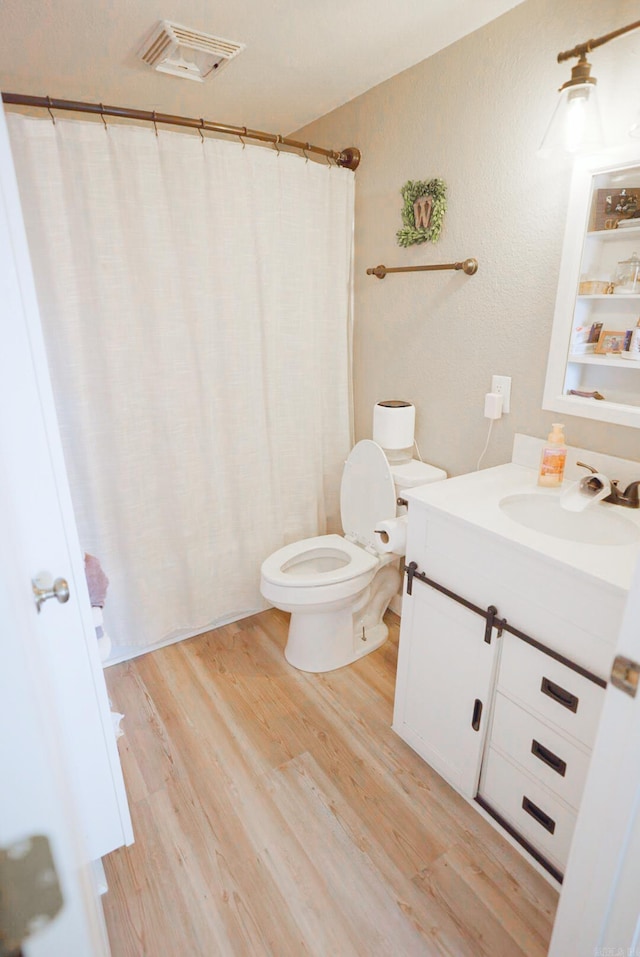 bathroom with wood-type flooring, toilet, and vanity