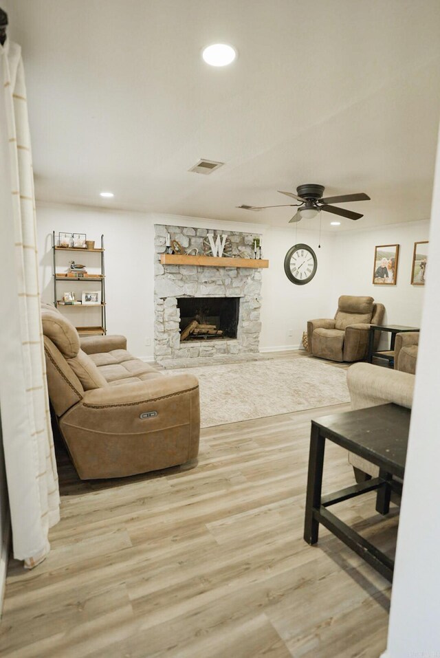 living room with a fireplace, ceiling fan, and light wood-type flooring