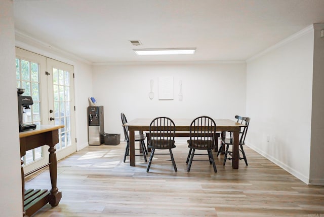 dining area featuring french doors, crown molding, and light hardwood / wood-style flooring