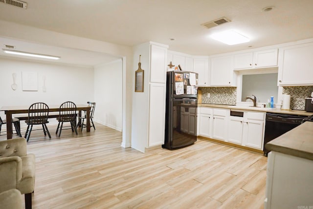 kitchen with light hardwood / wood-style floors, tasteful backsplash, black appliances, and white cabinets