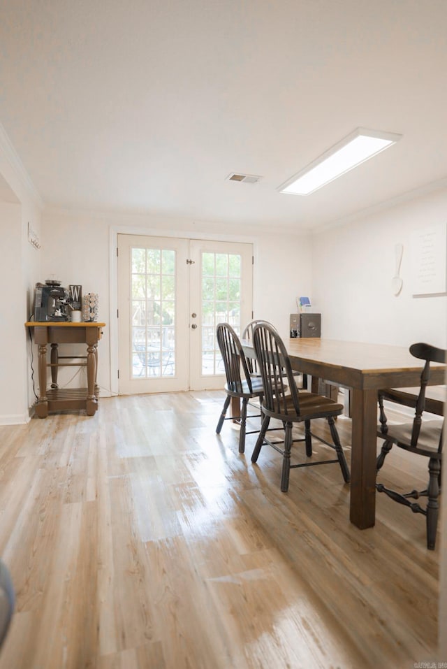 dining space featuring light wood-type flooring, french doors, and crown molding