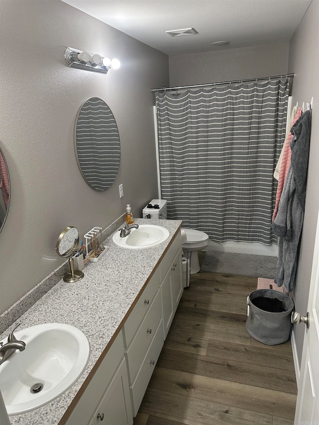 bathroom featuring hardwood / wood-style floors, toilet, and dual vanity