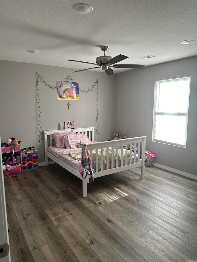 bedroom featuring hardwood / wood-style floors, ceiling fan, and a textured ceiling