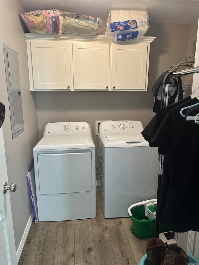 clothes washing area featuring cabinets, independent washer and dryer, electric panel, and wood-type flooring