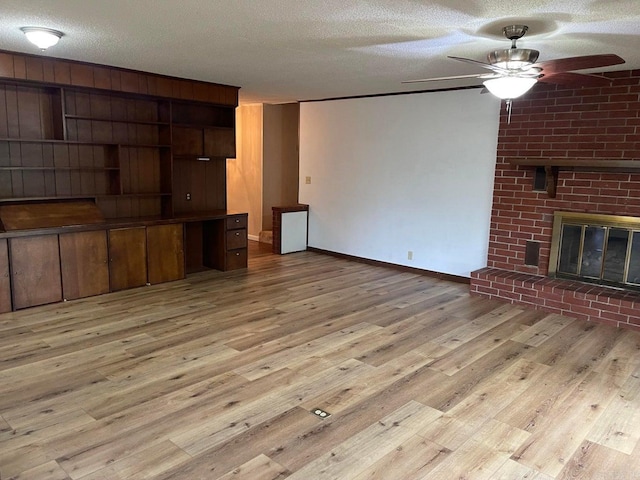 unfurnished living room with a textured ceiling, light hardwood / wood-style flooring, ceiling fan, and a fireplace