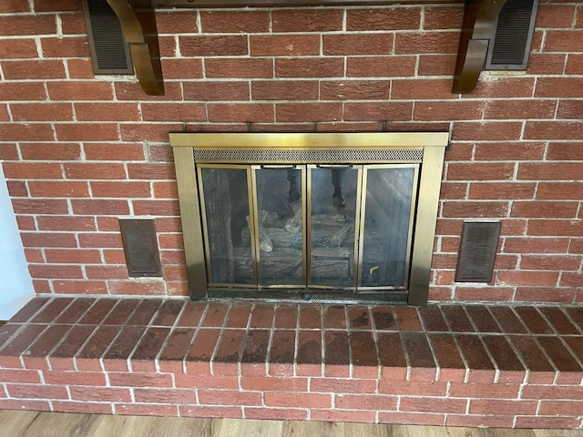 room details featuring a brick fireplace and wood-type flooring