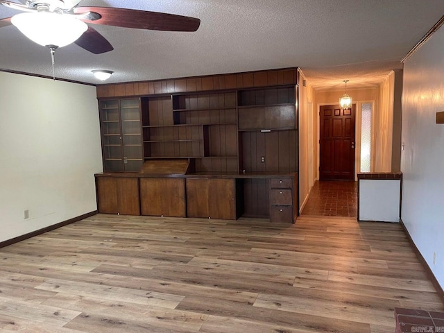 unfurnished living room featuring ceiling fan, hardwood / wood-style flooring, ornamental molding, and a textured ceiling