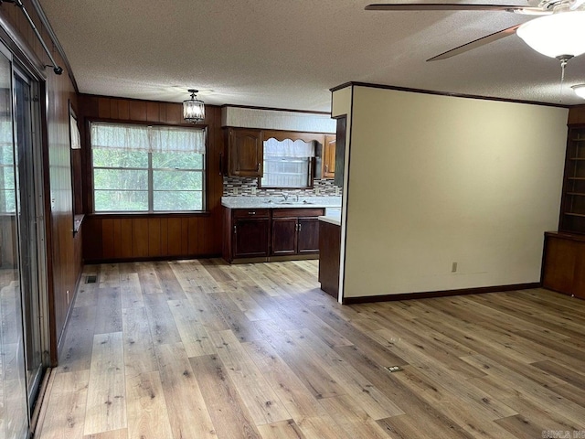 kitchen featuring ceiling fan, light wood-type flooring, a textured ceiling, and dark brown cabinetry