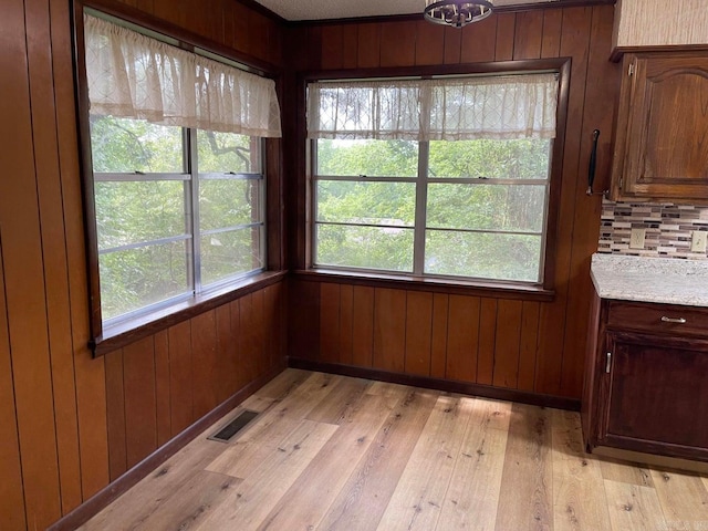 unfurnished dining area with wood walls and light hardwood / wood-style floors