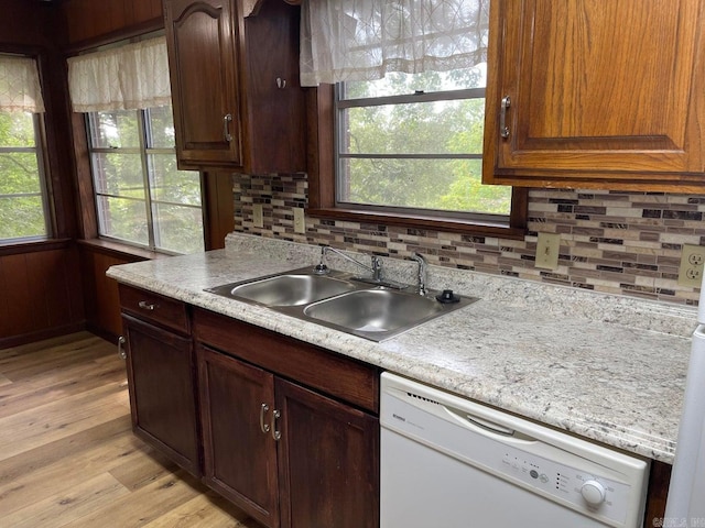 kitchen with sink, tasteful backsplash, light hardwood / wood-style flooring, and white dishwasher