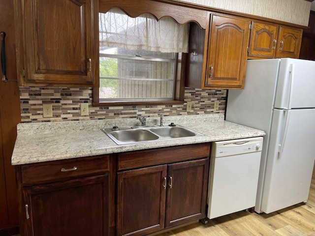 kitchen featuring sink, white appliances, light wood-type flooring, and backsplash