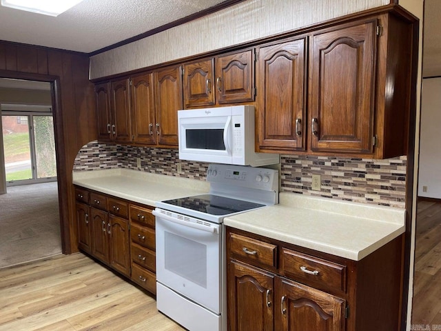 kitchen with backsplash, dark brown cabinets, white appliances, light hardwood / wood-style floors, and a textured ceiling