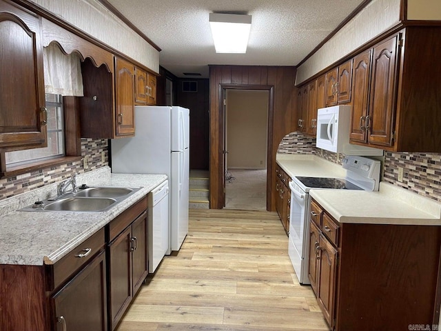 kitchen featuring tasteful backsplash, light hardwood / wood-style floors, sink, a textured ceiling, and white appliances