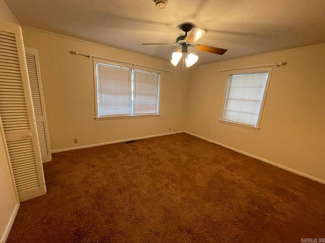 unfurnished bedroom featuring ceiling fan, a closet, and dark colored carpet