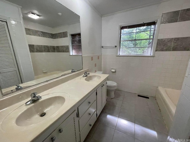 bathroom with tile walls, toilet, dual bowl vanity, and tile patterned floors