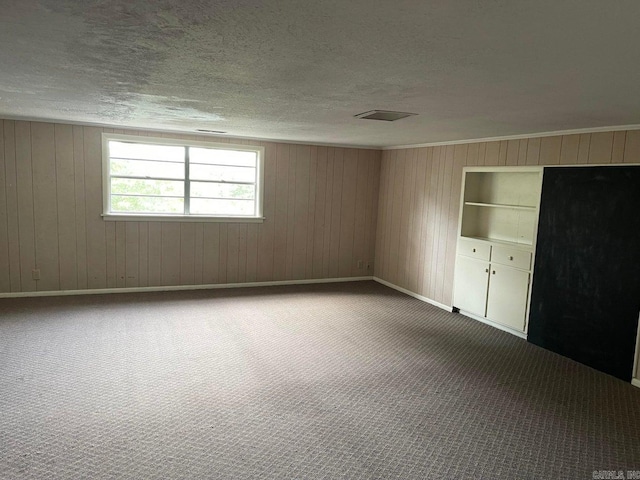 unfurnished bedroom with carpet flooring, a textured ceiling, and wood walls