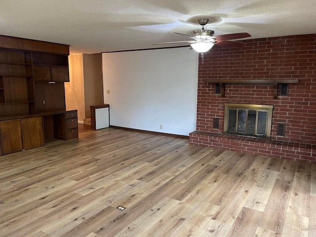 unfurnished living room featuring a textured ceiling, brick wall, ceiling fan, and light wood-type flooring