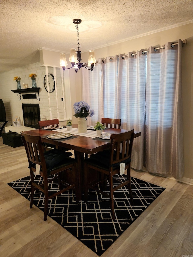 dining space with a notable chandelier, crown molding, a textured ceiling, and wood finished floors