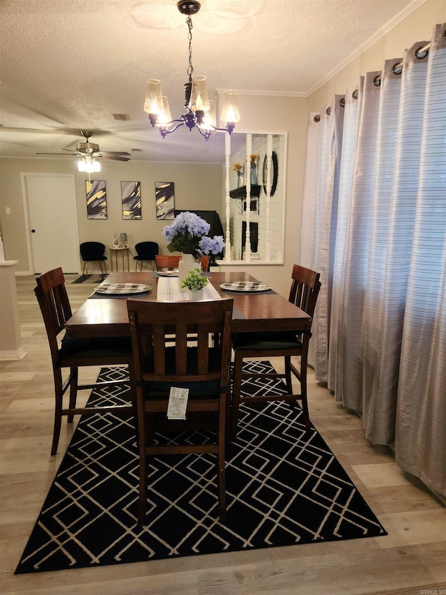 dining area with ornamental molding, visible vents, a textured ceiling, and light wood finished floors