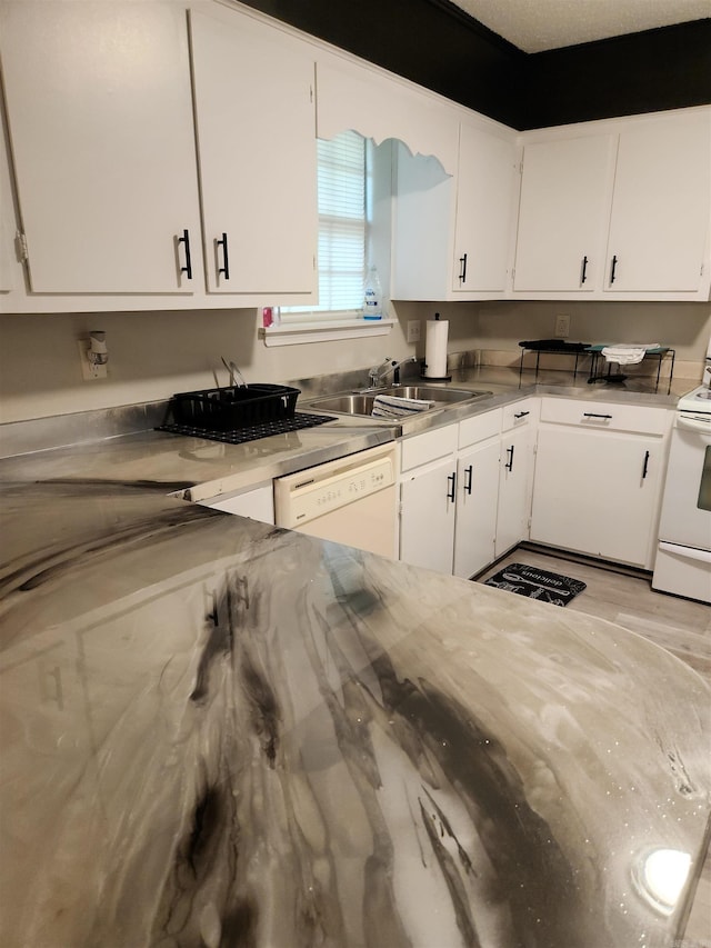 kitchen with white appliances, stainless steel counters, a sink, and white cabinetry