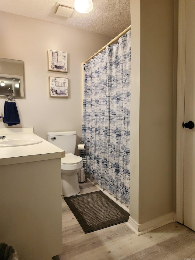 full bathroom featuring visible vents, a textured ceiling, toilet, and wood finished floors