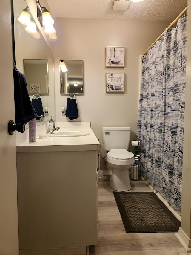 full bath featuring a shower with shower curtain, toilet, a textured ceiling, vanity, and wood finished floors