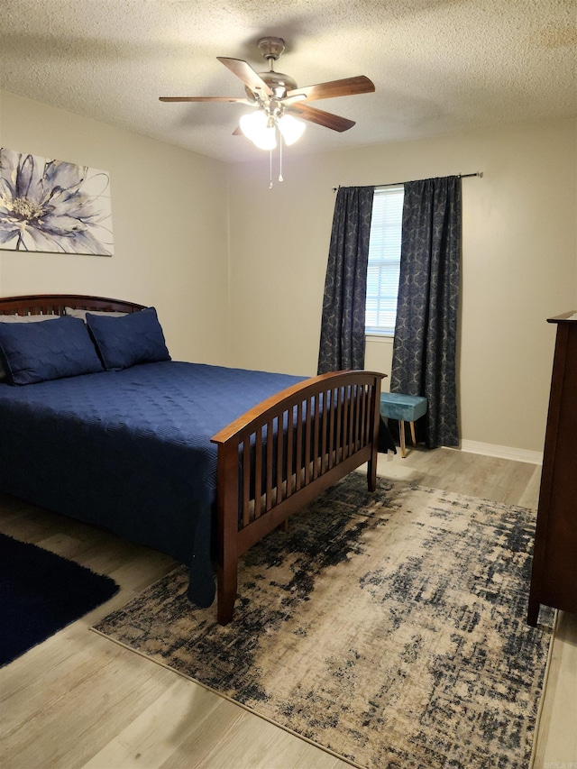 bedroom with a textured ceiling, ceiling fan, and wood finished floors