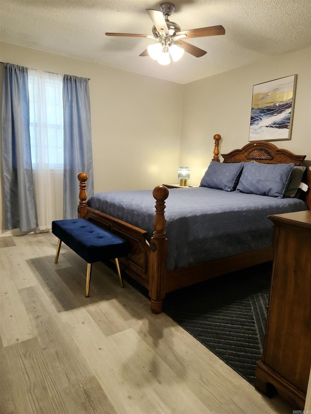 bedroom with a textured ceiling, wood finished floors, and a ceiling fan