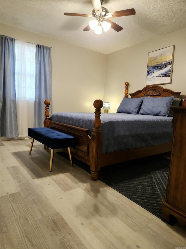 bedroom with a ceiling fan, a textured ceiling, and wood finished floors