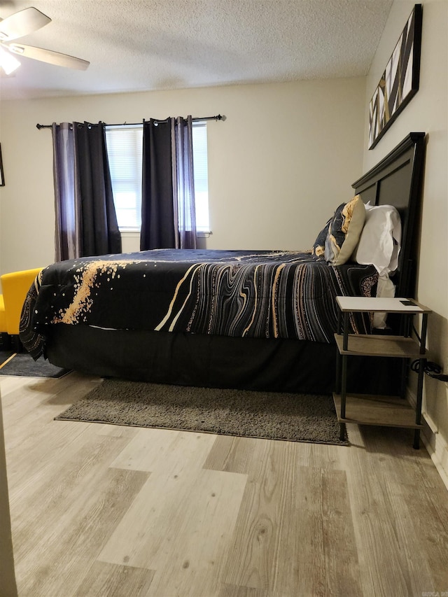 bedroom with a textured ceiling, a ceiling fan, and wood finished floors