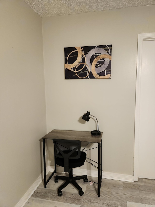 home office featuring a textured ceiling, wood finished floors, and baseboards