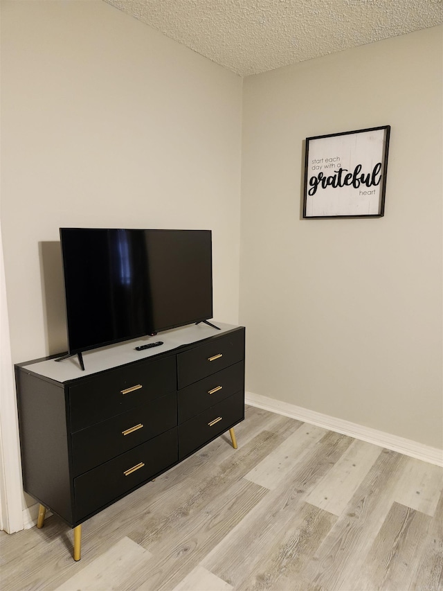 interior space featuring a textured ceiling, wood finished floors, and baseboards