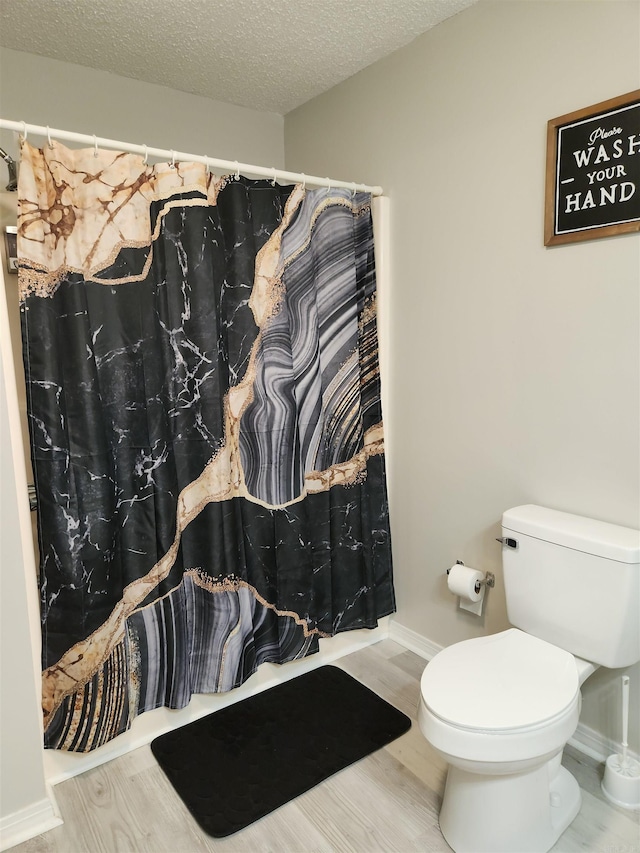 bathroom featuring a textured ceiling, wood finished floors, toilet, and a shower with curtain