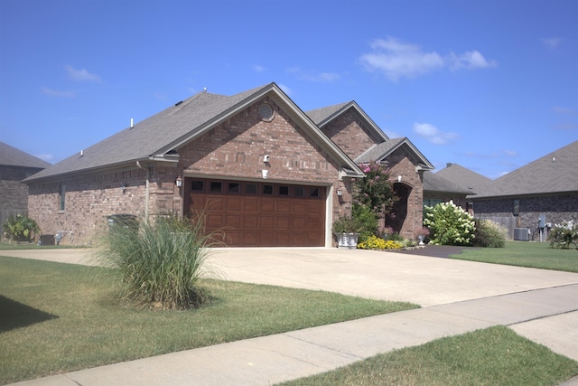 view of front of home with a front yard, a garage, and cooling unit