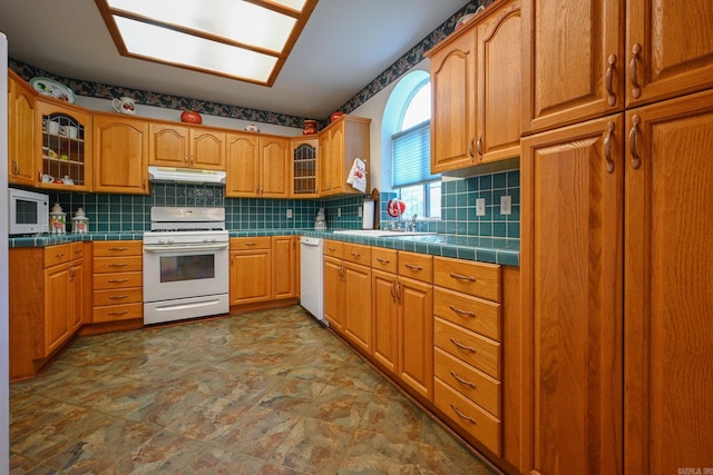 kitchen with backsplash, tile patterned floors, tile countertops, sink, and white appliances